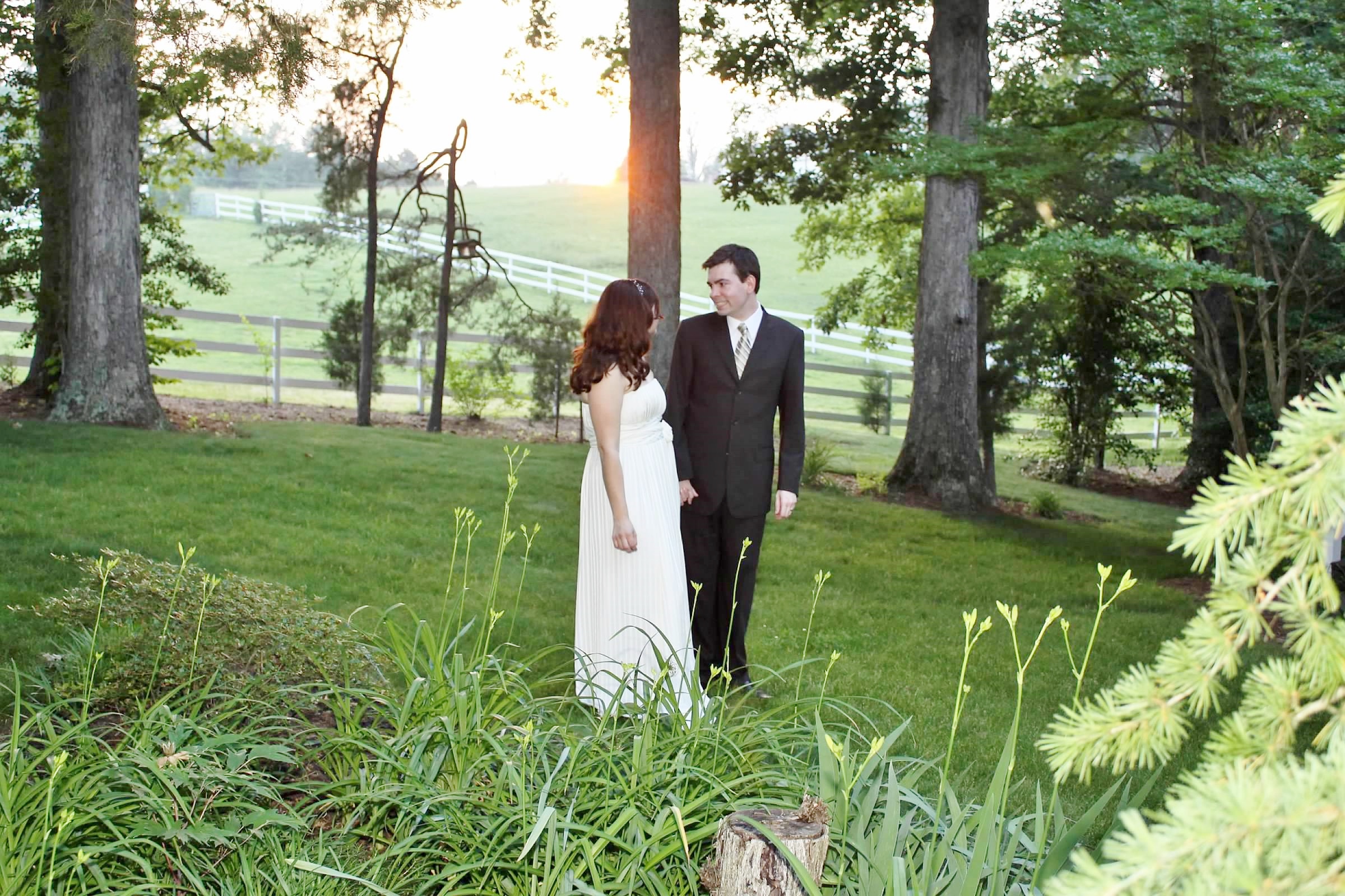 Green grass and daylilies about to bloom in front of bride and groom.