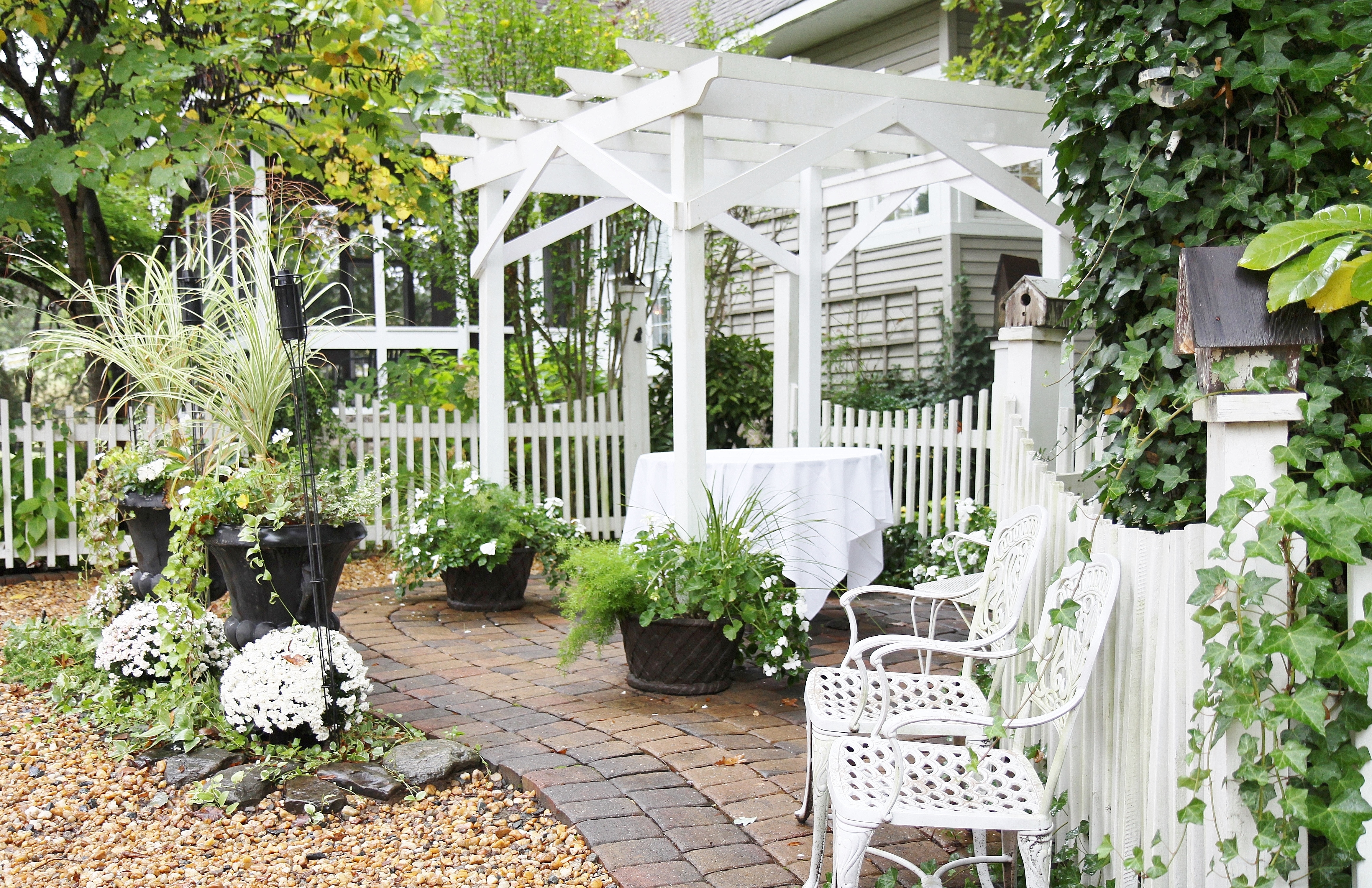 Sign-in table with white tablecloth is under small pergola.